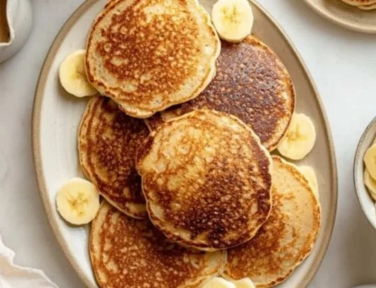 Healthy banana oatmeal pancakes stacked on a plate with fresh fruits