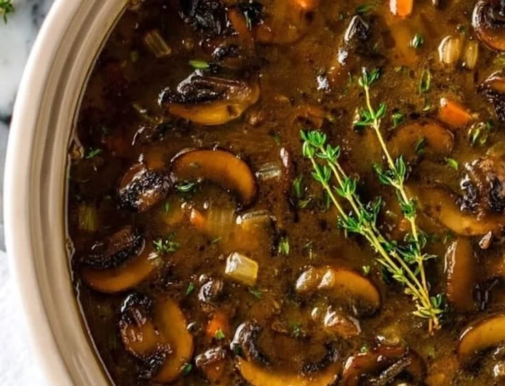 Healthy mushroom soup in a bowl with fresh herbs and ingredients