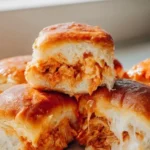 Buffalo Chicken Sliders topped with creamy blue cheese and served on a platter.