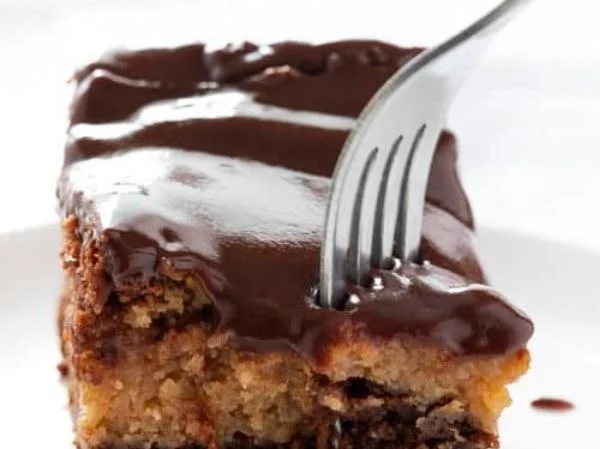 Slice of Chocolate Peanut Butter Ooey Gooey Cake topped with chocolate drizzle.
