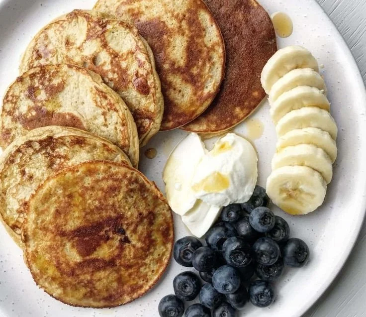 Delicious high protein pancakes stacked with fresh fruit on a plate