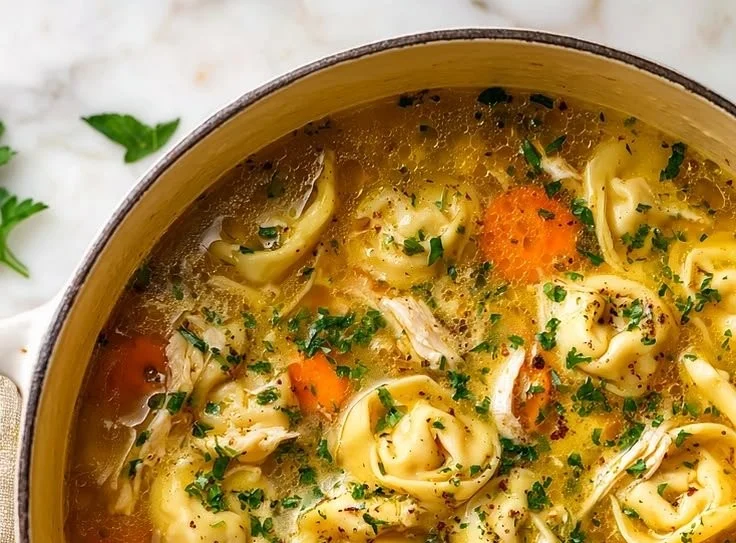 Bowl of homemade chicken tortellini soup with fresh herbs and vegetables