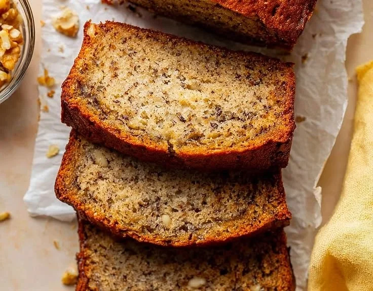 Sliced old fashioned banana bread on a wooden cutting board.