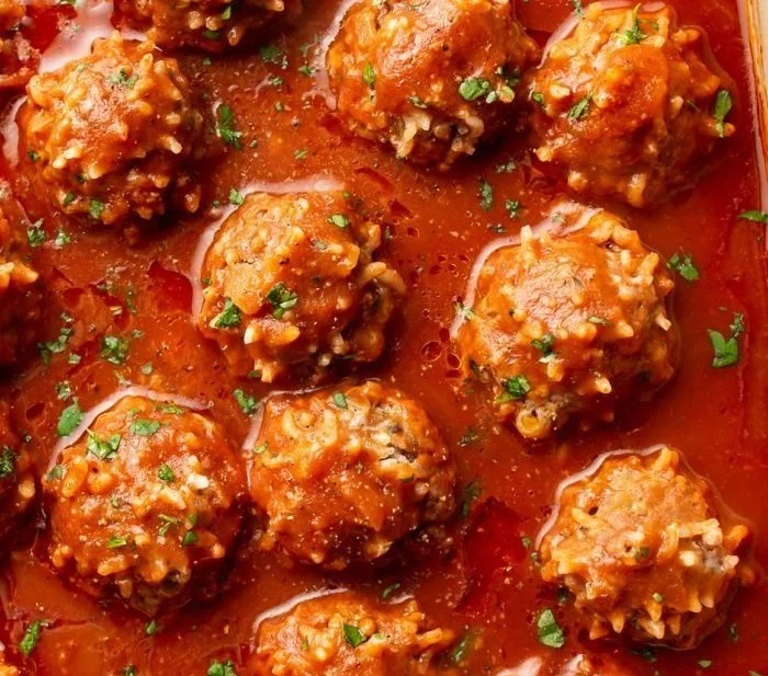 Delicious Porcupine Meatballs served with a side of sauce and garnished with herbs.