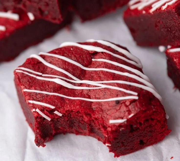 Delicious Red Velvet Brownies topped with cream cheese frosting and sprinkles.