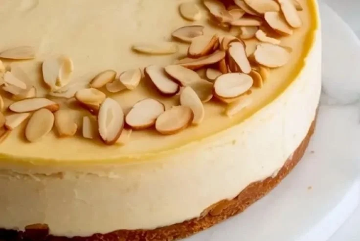 Slice of decadent amaretto cheesecake topped with almonds on a white plate