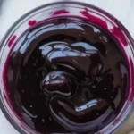 Delicious blueberry curd served in a jar topped with fresh blueberries.