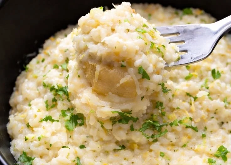 Bowl of creamy Parmesan rice garnished with parsley on a wooden table