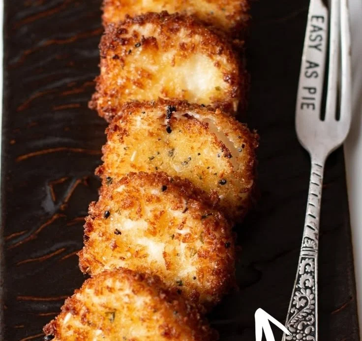 Crispy fried goat cheese bites with a drizzle of tangy honey on a plate