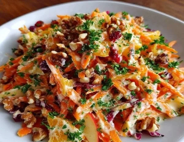 Crunchy apple carrot salad with creamy citrus dressing on a serving plate
