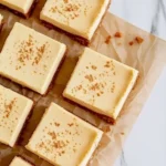 Delicious eggnog cheesecake bars topped with whipped cream and nutmeg.