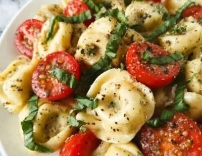 Delicious Garlic Parmesan Tortellini Salad in a bowl with fresh ingredients.