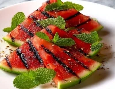 Grilled watermelon with mint served on a plate, garnished for a summer treat.