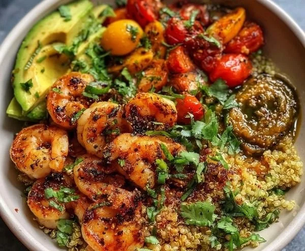 Healthy grilled shrimp and quinoa bowl garnished with fresh vegetables