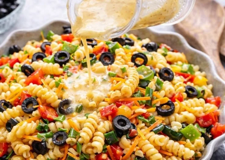 A colorful Italian pasta salad with vegetables and dressing served in a bowl.