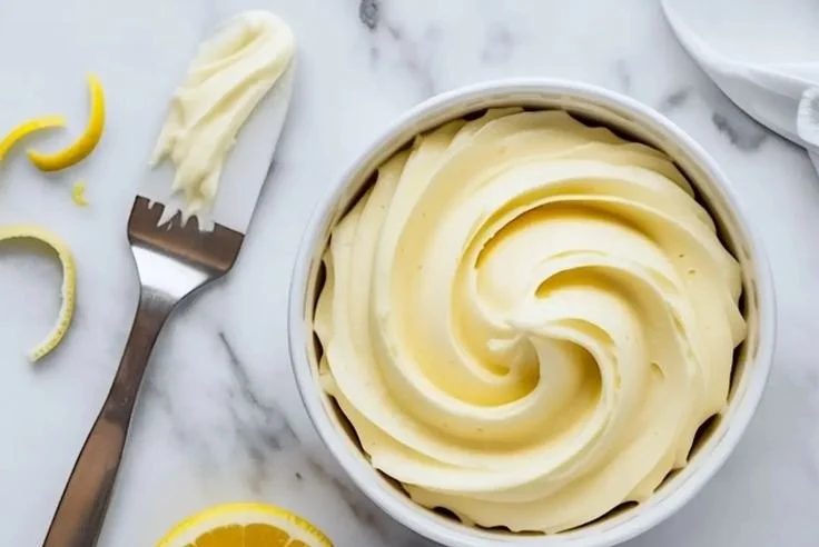 Lemon buttercream frosting on a cupcake with lemon slices.
