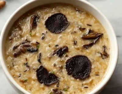 Bowl of wild rice soup with morel mushrooms, garnished with herbs.
