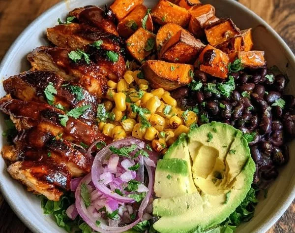 BBQ chicken sweet potato bowl topped with fresh ingredients and herbs