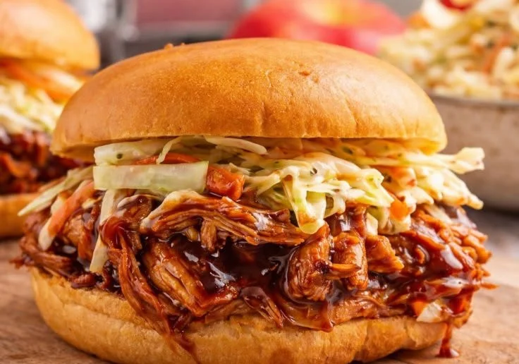 Delicious BBQ Pulled Chicken served with coleslaw and buns.