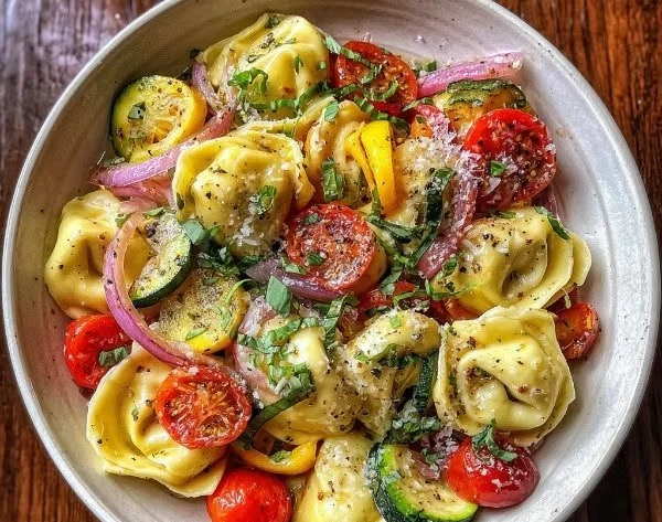 Bowl of cheese-filled tortellini with colorful summer vegetables.