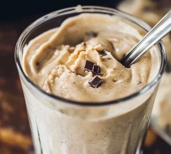 Chocolate peanut butter protein shake in a glass with a straw
