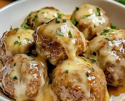 Crock Pot French Onion Meatballs served with melted cheese and fresh herbs