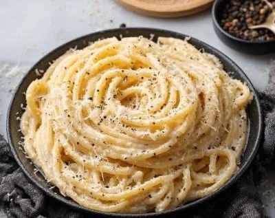 Bowl of Bucatini Cacio e Pepe garnished with black pepper and parmesan