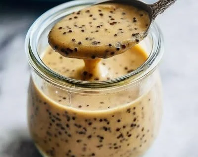 Creamy balsamic dressing in a glass jar surrounded by fresh salad ingredients.