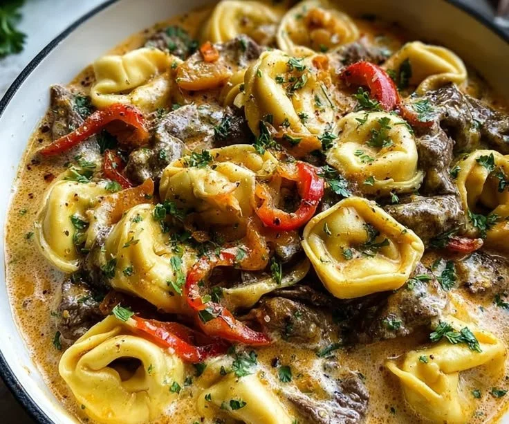 Cheesesteak tortellini dish with provolone sauce served in a cozy dinner setting