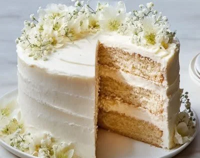 Easy white wedding cake decorated with fresh flowers and cake topper.