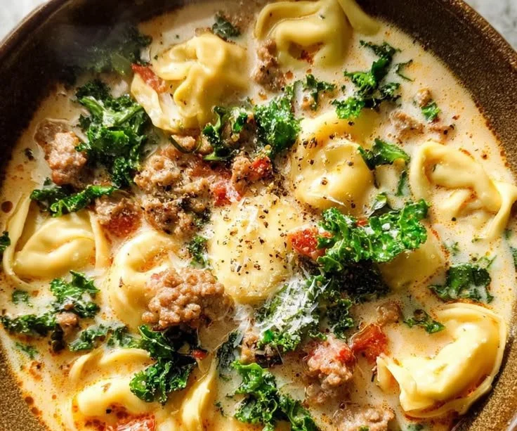 Bowl of Italian tortellini soup garnished with herbs and vegetables